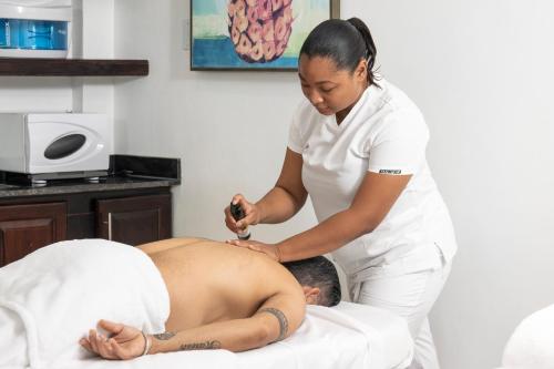 Uma mulher num spa a massajar um homem. em Sago Palm Hotel em Ocho Rios