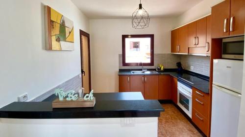 una cucina con armadi in legno e piano di lavoro nero di Bahia Sol Dream -Caleta de Fuste- a Caleta De Fuste