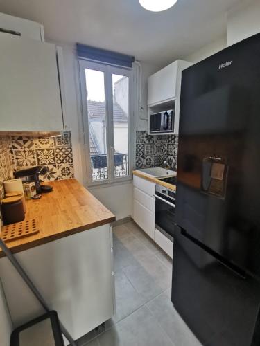 d'une cuisine équipée d'un réfrigérateur noir et d'une fenêtre. dans l'établissement Charmant studio à Montmorency, à Montmorency