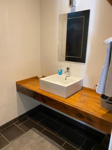 La salle de bains est pourvue d'un lavabo blanc et d'un miroir. dans l'établissement Gites Le Grand Tornage, à Évaux-les-Bains