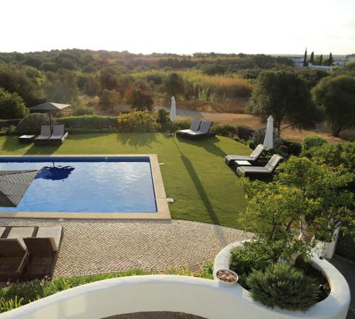 a swimming pool in a yard with two lounges at Casa Flor de Sal in Moncarapacho