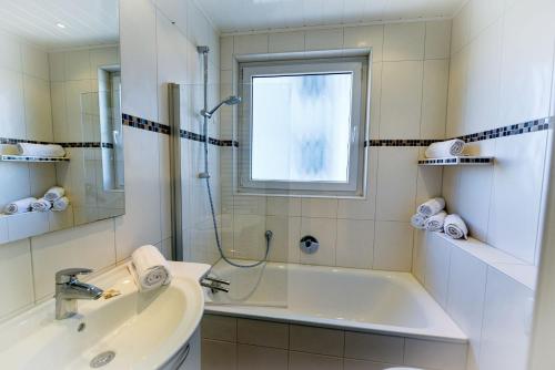 ein Bad mit einer Badewanne, einem Waschbecken und einem Fenster in der Unterkunft Strandhochhaus SJ07 in Cuxhaven