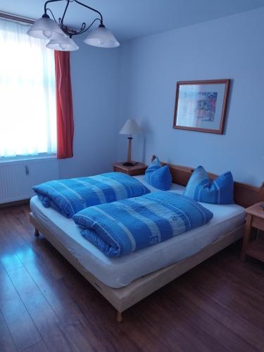 a bed with blue pillows on it in a room at pension-Zur alten Bäckerei in Golßen