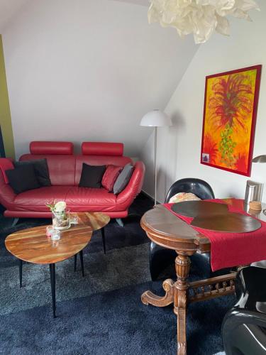 a living room with a red couch and tables at Ferienwohnung Lagedeich in Südermarsch