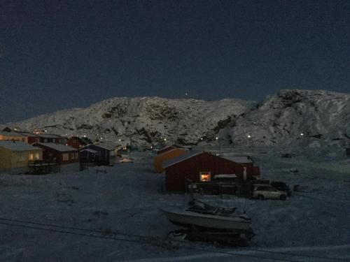 a town with a boat in the snow at night at B&B Ire in Ilulissat