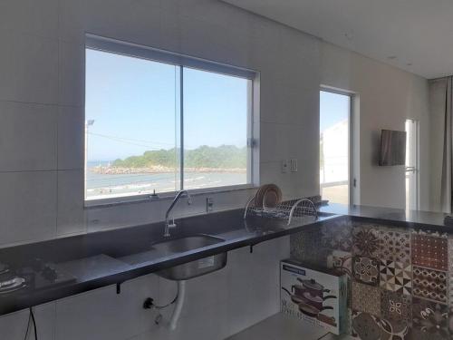 a kitchen with a sink and a view of the beach at Vista Deslumbrante praia Barra da Lagoa in Florianópolis