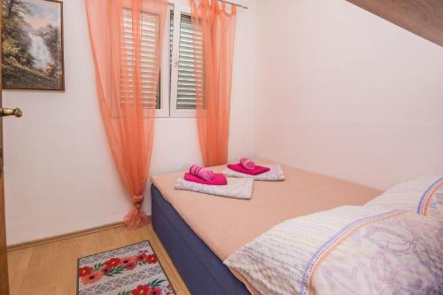 - une chambre avec 2 chaussons roses sur un lit dans l'établissement Apartment Emina, à Batalaži