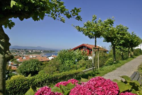 a garden with pink flowers and a house on a hill at Hotel & Appartements Gochoki in Bidart