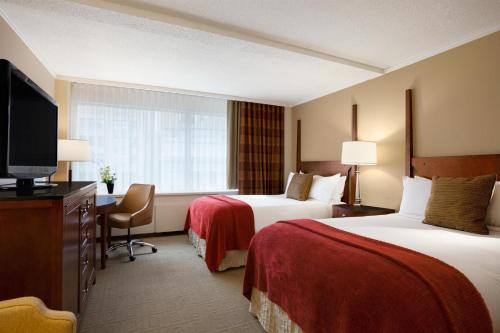 a hotel room with two beds and a flat screen tv at Fairmont Winnipeg in Winnipeg