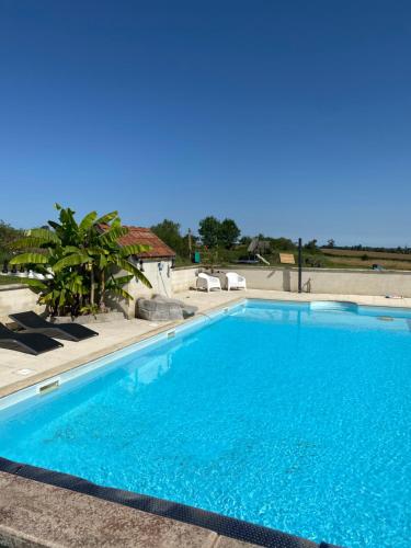a large swimming pool with blue water in a yard at Gites Le Grand Tornage in Évaux-les-Bains