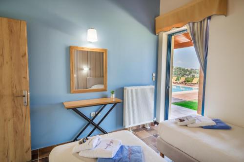 a room with two beds and a table and a mirror at Villa Givera in Giannoudi