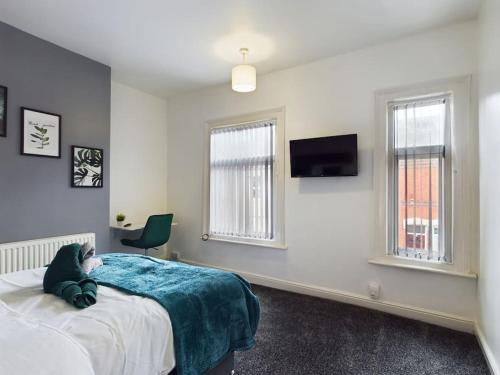 a bedroom with a bed and a tv and two windows at Birks House By RMR Accommodations - NEW - Sleeps 8 - Modern - Parking in Stoke on Trent