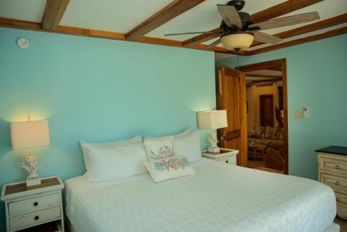 a bedroom with a white bed with a ceiling fan at Large Ocean Front Home Close to Village - Surfside Gecko in Seine Bight Village