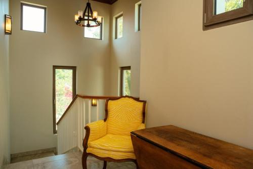 a yellow chair in a room with a table and windows at Large Ocean Front Home Close to Village - Surfside Gecko in Seine Bight Village
