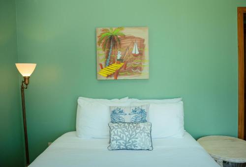 a bedroom with a white bed with a picture on the wall at Large Ocean Front Home Close to Village - Surfside Gecko in Seine Bight Village