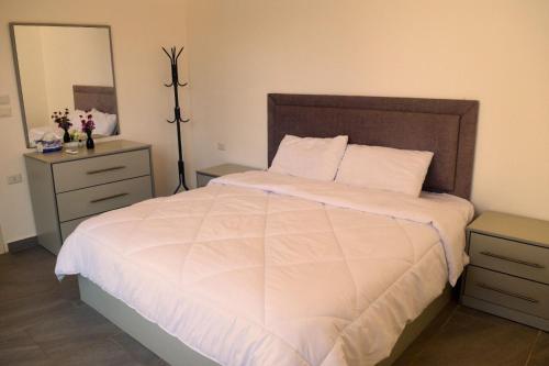 a bedroom with a large white bed with a mirror at Gloria Chalet in Al Rama