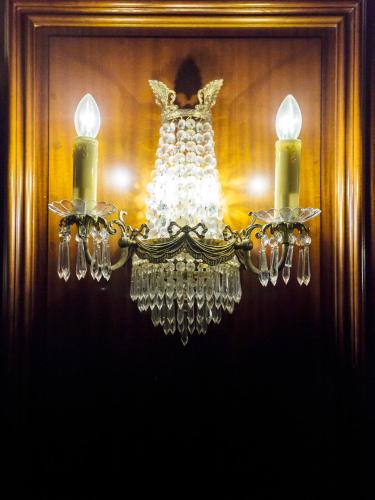 a chandelier with two candles in front of a mirror at Hôtel Irlande in Lourdes