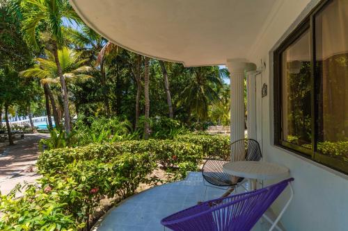 a porch with a table and chairs and palm trees at Hotel Cocoliso Island Resort in Isla Grande