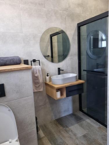 La salle de bains est pourvue d'un lavabo et d'un miroir. dans l'établissement Villa 206 Clarens Golf Estate, à Clarens