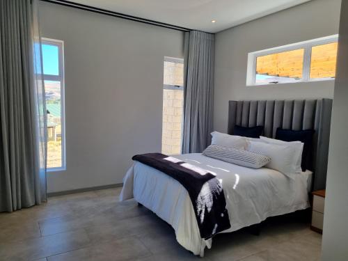 1 dormitorio con 1 cama y 2 ventanas en Villa 206 Clarens Golf Estate, en Clarens