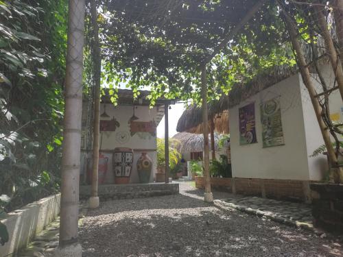 un edificio con techo de paja y árboles delante de él en El Leon Feliz Palomino, en Palomino