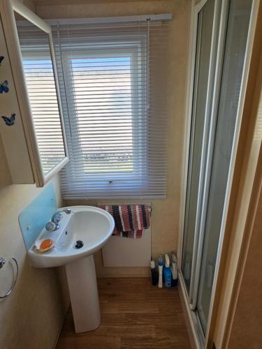 a small bathroom with a sink and a window at Liberty Caravan Hire in Chapel Saint Leonards