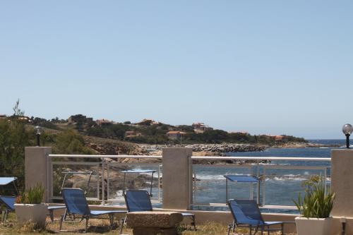 a patio with chairs and a view of the ocean at Hotel St Joseph in Algajola