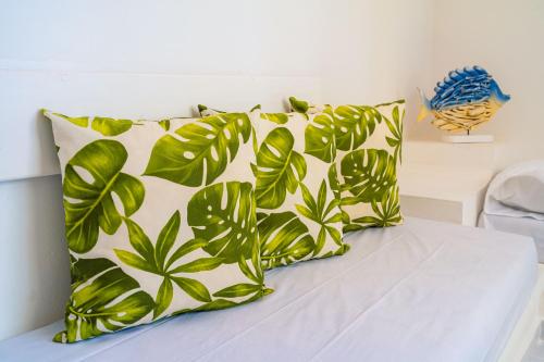 a bed with two pillows with green leaves on it at Hotel Cocoliso Island Resort in Isla Grande