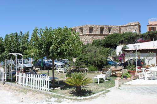 a garden with a white fence and tables and chairs at Hotel St Joseph in Algajola