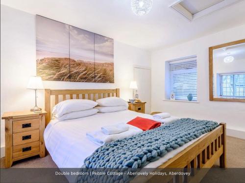 a bedroom with a large bed and a painting on the wall at Pebble Cottage in Aberdyfi