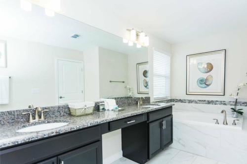 La salle de bains est pourvue de 2 lavabos et d'un grand miroir. dans l'établissement Modern Vacation Home with Private Pool CG1593, à Davenport