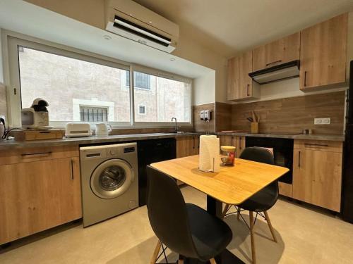 eine Küche mit einem Tisch und einer Waschmaschine in der Unterkunft L’amandier - Appartement in Paulhan