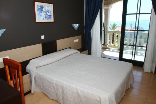 a bedroom with a white bed and a large window at Apartamentos Coral Do Mar II in Portonovo