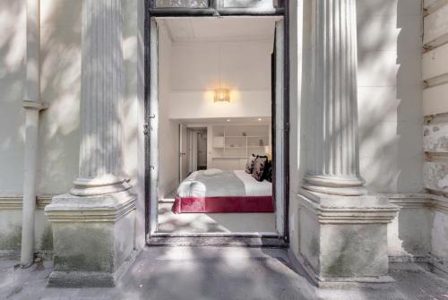 a bedroom with a bed in a room with columns at Victorian ARCHITECT Flat with Long BALCONY in London
