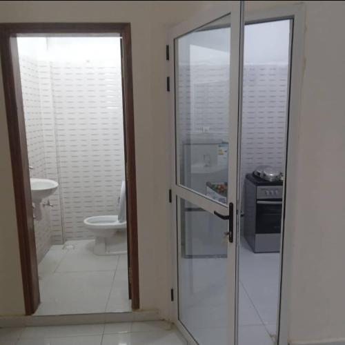 a bathroom with a toilet and a glass door at Salam in Saint-Louis