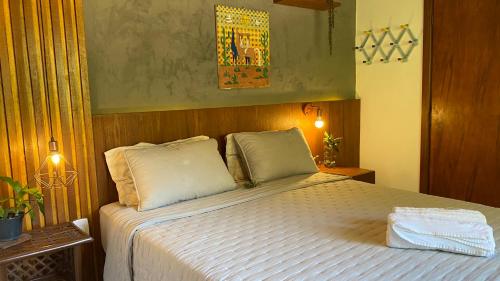 une chambre avec un lit avec des draps blancs et des oreillers dans l'établissement Vila Verde Perto, à Lençóis
