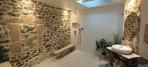 a bathroom with a sink and a stone wall at L'éphémère in Saint Dionizy