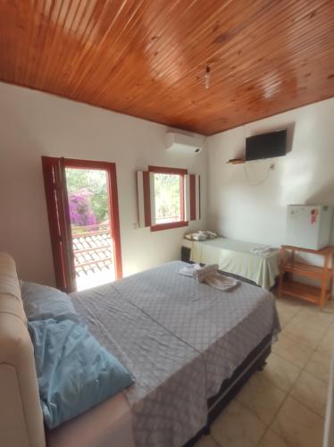 a bedroom with a bed and a television and a table at Pousada Batihá - beira rio in Pirenópolis