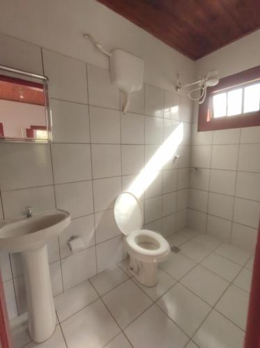 a white bathroom with a toilet and a sink at Pousada Batihá - beira rio in Pirenópolis