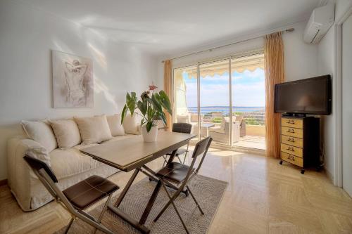 a living room with a couch and a table and a television at IMMOGROOM - 1 Bedroom - Terasse - Sea View - AC - Wifi in Cannes