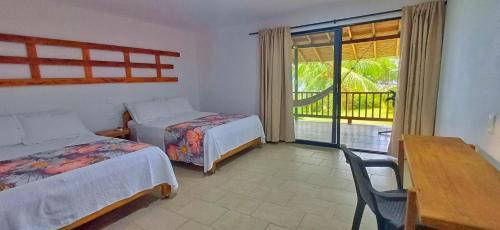 a bedroom with two beds and a table and a balcony at Playa de Oro Lodge in Bahía Solano