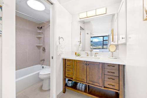 a bathroom with a sink and a toilet and a mirror at Stylish Unit Near Waikiki Beach with Free Parking! in Honolulu