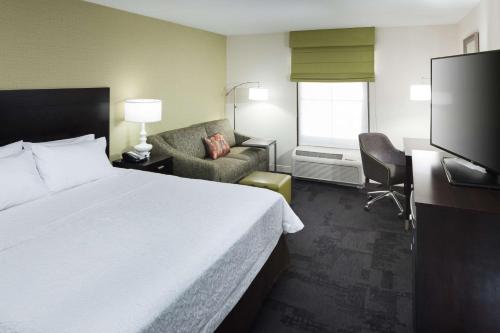 a hotel room with a large bed and a chair at Hampton Inn & Suites Gainesville Downtown in Gainesville