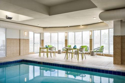 einen Pool mit Stühlen und Tischen neben einem Zimmer mit Fenstern in der Unterkunft Hilton Garden Inn Fort Collins in Fort Collins