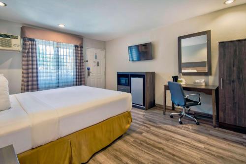 a hotel room with a bed and a desk and a chair at Studio 6 Rosemead, CA in Rosemead