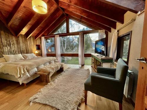 a bedroom with a bed and a tv and a chair at Hogar de Montaña in Villa La Angostura