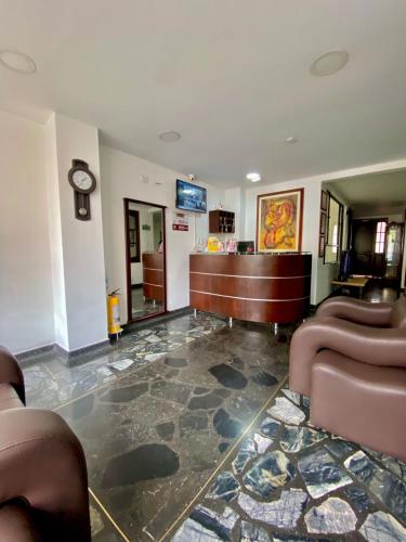 a lobby with a waiting room with two chairs and a counter at Ayenda Hotel Posada Leon in Pasto