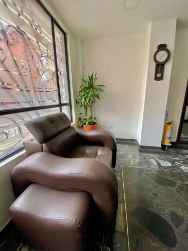 a waiting room with a brown reclining chair and a clock at Hotel Posada Leon in Pasto