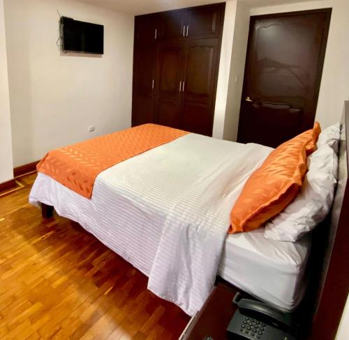 a bed with an orange and white comforter in a room at Ayenda Hotel Posada Leon in Pasto