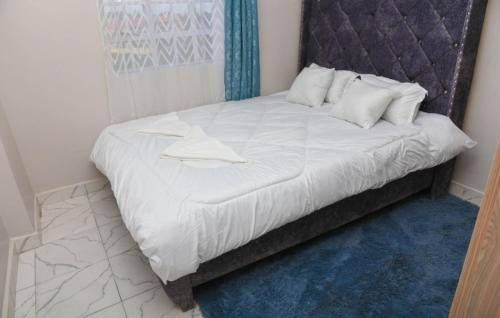 ein weißes Bett mit Kopfteil in einem Zimmer in der Unterkunft Poly's Place Airbnb in Nairobi